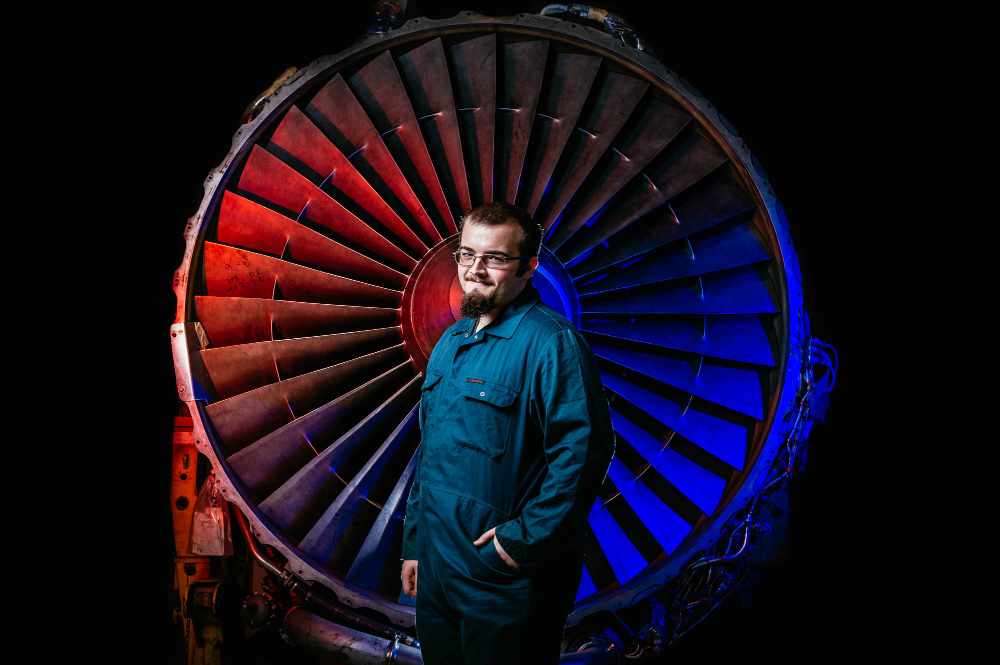 A photo of an engineering student standing in front of a jet propeller