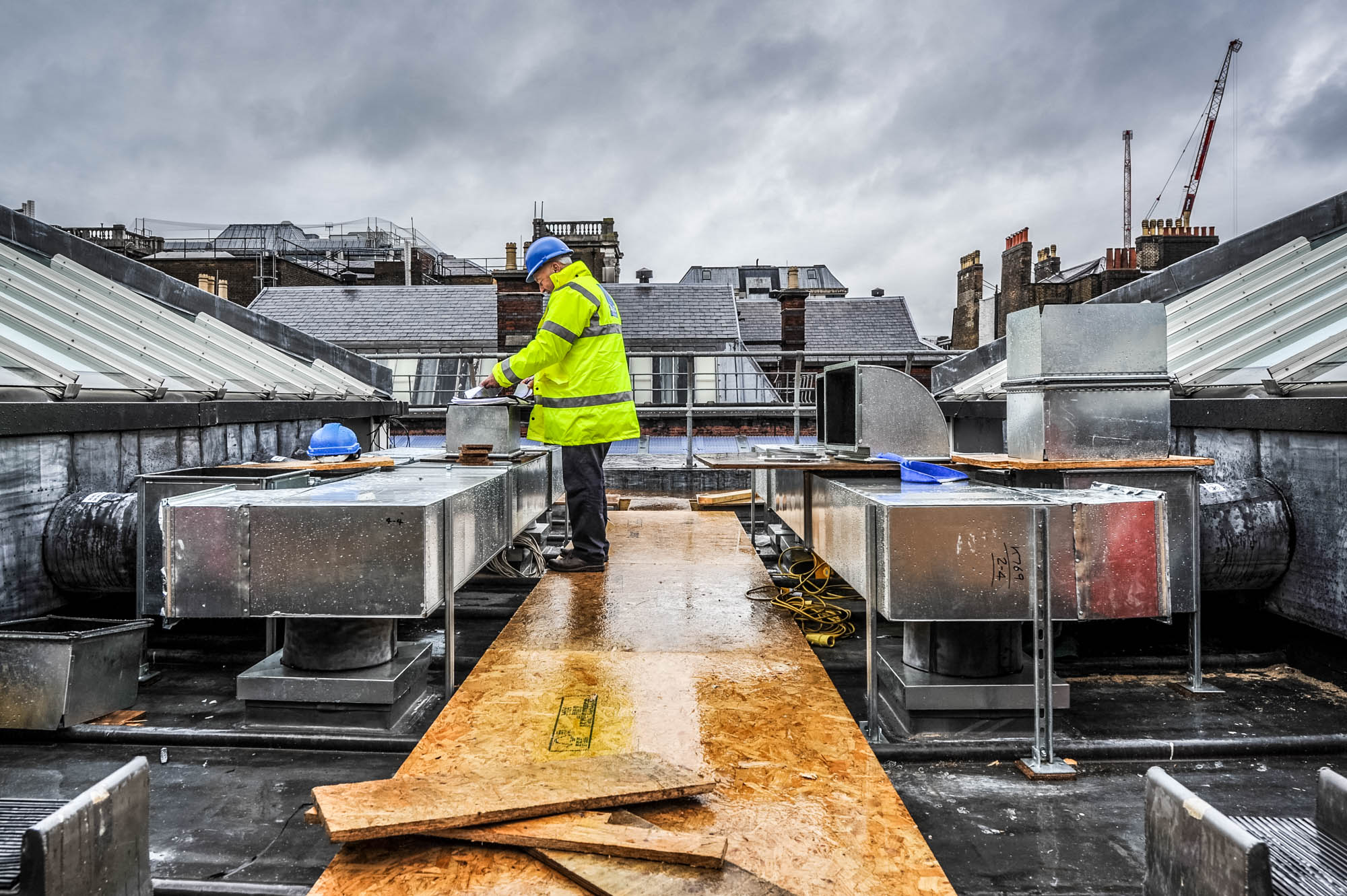 A photo of an architect reviewing plans on the rooftop of a building in central london